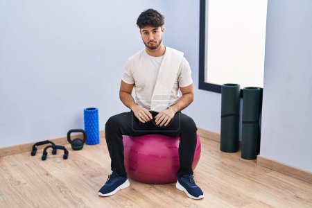 Photo for Hispanic man with beard sitting on pilate balls at yoga room depressed and worry for distress, crying angry and afraid. sad expression. - Royalty Free Image