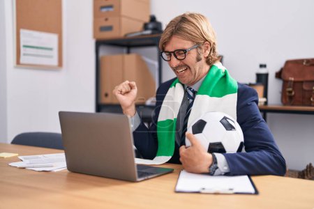 Foto de Caucasian man with mustache working at the office supporting football team screaming proud, celebrating victory and success very excited with raised arms - Imagen libre de derechos