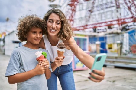 Foto de Mother and son eating ice cream make selfie by the smartphone at theme park - Imagen libre de derechos