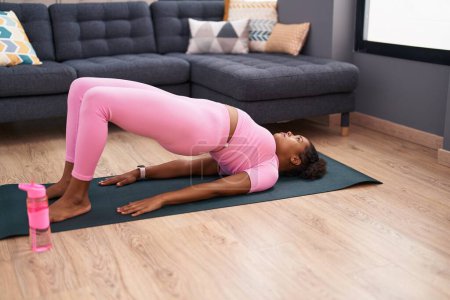 Téléchargez les photos : Femme afro-américaine faisant de l'exercice de yoga à la maison - en image libre de droit