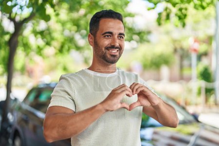 Téléchargez les photos : Young hispanic man smiling confident doing heart gesture with hands at street - en image libre de droit