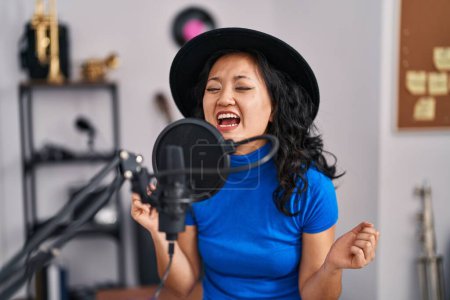 Téléchargez les photos : Jeune artiste chinoise chantant au studio de musique - en image libre de droit