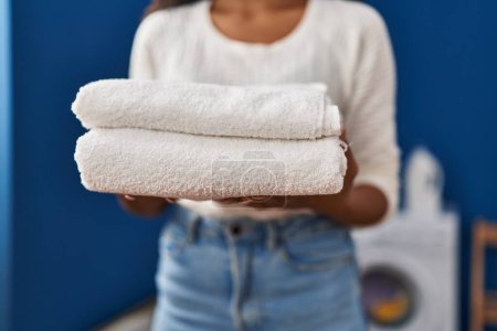 Téléchargez les photos : Young latin woman holding folded towels at laundru room - en image libre de droit
