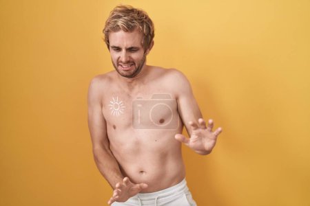 Photo for Caucasian man standing shirtless wearing sun screen disgusted expression, displeased and fearful doing disgust face because aversion reaction. - Royalty Free Image