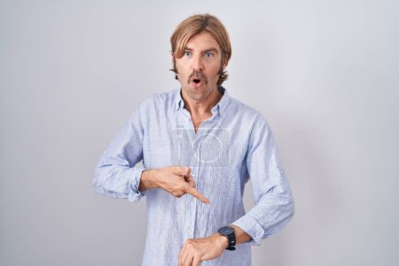 Foto de Caucasian man with mustache standing over white background in hurry pointing to watch time, impatience, upset and angry for deadline delay - Imagen libre de derechos