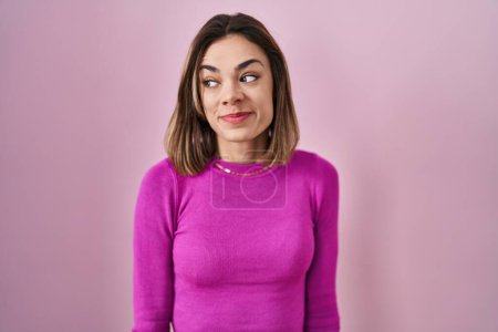 Foto de Hispanic woman standing over pink background smiling looking to the side and staring away thinking. - Imagen libre de derechos