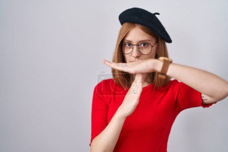 Téléchargez les photos : Jeune femme rousse debout portant des lunettes et un béret faisant un geste avec les mains, frustré et sérieux visage - en image libre de droit