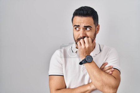 Photo for Young hispanic man with beard wearing casual clothes over white background looking stressed and nervous with hands on mouth biting nails. anxiety problem. - Royalty Free Image
