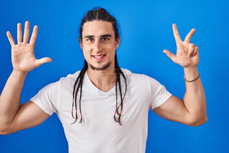 Photo for Hispanic man with long hair standing over blue background showing and pointing up with fingers number eight while smiling confident and happy. - Royalty Free Image