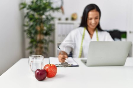 Photo for Young latin woman wearing nutritionist uniform working at clinic - Royalty Free Image