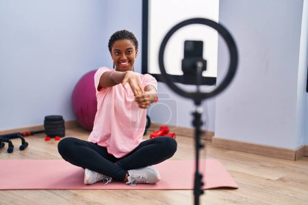 Photo for African american woman smiling confident having online stretch class at sport center - Royalty Free Image