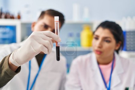 Téléchargez les photos : Homme et femme scientifiques partenaires analysant tube à essai sanguin au laboratoire - en image libre de droit