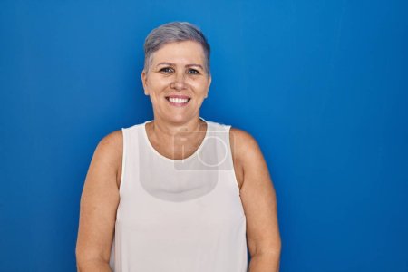 Photo for Middle age caucasian woman standing over blue background relaxed with serious expression on face. simple and natural looking at the camera. - Royalty Free Image