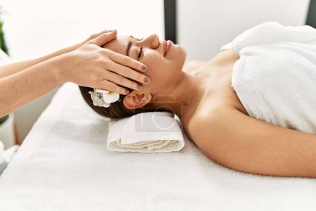 Photo for Young latin woman relaxed having face massage at beauty center - Royalty Free Image