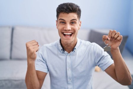 Photo for Young hispanic man holding keys of new home screaming proud, celebrating victory and success very excited with raised arm - Royalty Free Image
