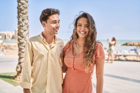 Téléchargez les photos : Homme et femme couple souriant confiant et s'embrassant au bord de la mer - en image libre de droit