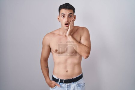 Photo for Handsome hispanic man standing shirtless afraid and shocked, surprise and amazed expression with hands on face - Royalty Free Image