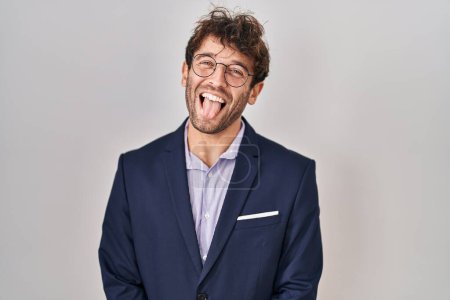 Foto de Hispanic business man wearing glasses sticking tongue out happy with funny expression. emotion concept. - Imagen libre de derechos