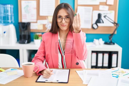 Téléchargez les photos : Jeune femme hispanique travaillant au bureau portant des lunettes faisant geste italien avec la main et les doigts expression confiante - en image libre de droit