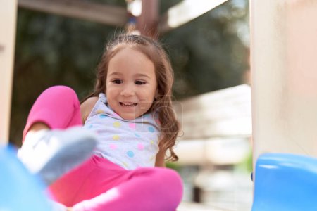 Téléchargez les photos : Adorable hispanic girl sitting on slide playing at park playground - en image libre de droit