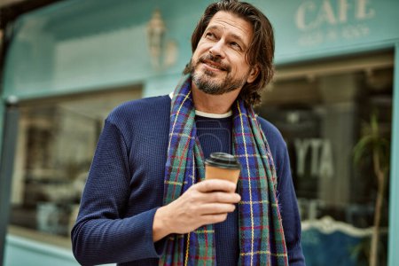Foto de Hombre guapo de mediana edad bebiendo una taza de café para llevar en la ciudad - Imagen libre de derechos