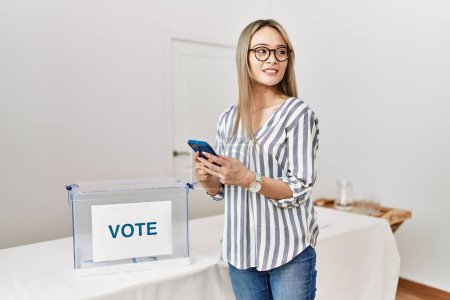 Photo for Young chinese woman using smartphone voting at electoral college - Royalty Free Image