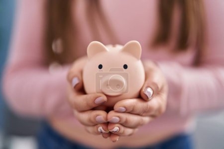 Photo for Young woman holding piggy bank at home - Royalty Free Image
