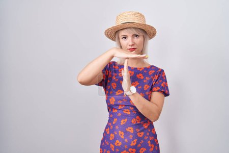 Téléchargez les photos : Young caucasian woman wearing flowers dress and summer hat doing time out gesture with hands, frustrated and serious face - en image libre de droit