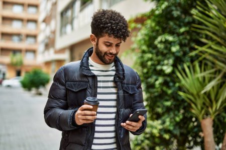 Téléchargez les photos : Jeune homme arabe utilisant smartphone en plein air à la ville - en image libre de droit