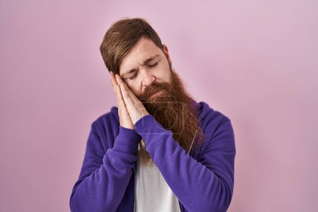 Photo for Caucasian man with long beard standing over pink background sleeping tired dreaming and posing with hands together while smiling with closed eyes. - Royalty Free Image