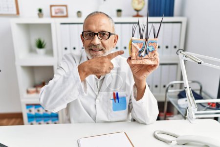 Téléchargez les photos : Mature doctor man holding model of human anatomical skin and hair smiling happy pointing with hand and finger - en image libre de droit