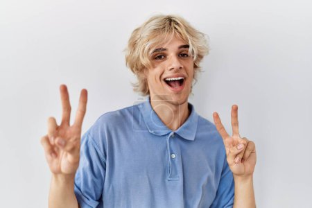 Téléchargez les photos : Young modern man standing over isolated background smiling looking to the camera showing fingers doing victory sign. number two. - en image libre de droit