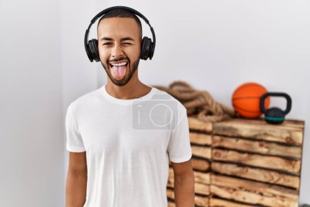 Photo for African american man listening to music using headphones at the gym sticking tongue out happy with funny expression. emotion concept. - Royalty Free Image