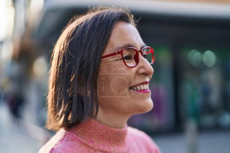 Foto de Mujer de mediana edad sonriendo confiada usando gafas en la calle - Imagen libre de derechos