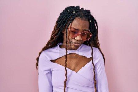 Foto de Mujer africana con el pelo trenzado de pie sobre fondo rosa guiño mirando a la cámara con expresión sexy, cara alegre y feliz. - Imagen libre de derechos