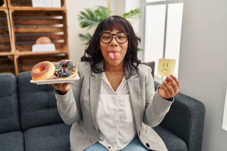 Photo for Hispanic therapist woman working on eating disorder sticking tongue out happy with funny expression. - Royalty Free Image