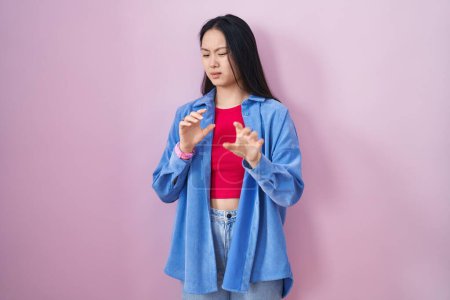 Photo for Young asian woman standing over pink background disgusted expression, displeased and fearful doing disgust face because aversion reaction. - Royalty Free Image