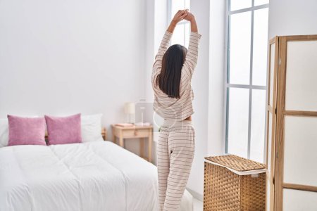 Photo for Young hispanic woman stretching arms standing at bedroom - Royalty Free Image