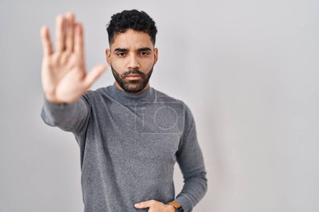 Photo for Hispanic man with beard standing over white background doing stop sing with palm of the hand. warning expression with negative and serious gesture on the face. - Royalty Free Image