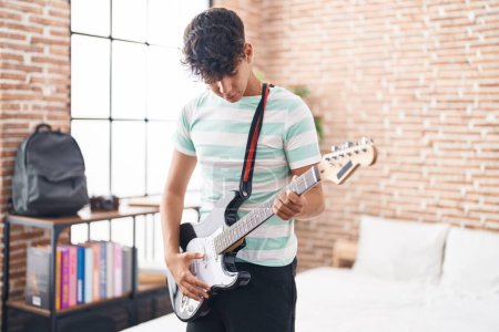 Téléchargez les photos : Jeune adolescent hispanique musicien jouant de la guitare électrique dans la chambre - en image libre de droit