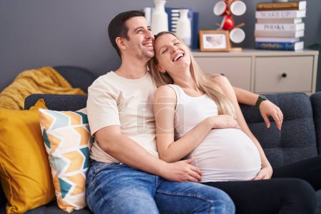 Photo for Man and woman couple expecting baby hugging each other at home - Royalty Free Image