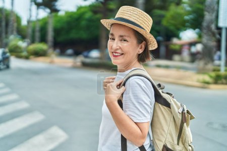 Foto de Mujer de mediana edad turista sonriendo confiado usando mochila en la calle - Imagen libre de derechos