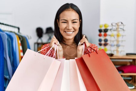 Photo for Young latin woman smiling confident holding shopping bags at clothing store - Royalty Free Image