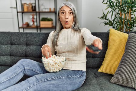 Téléchargez les photos : Moyen âge femme aux cheveux gris regarder un film à la maison - en image libre de droit