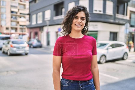 Foto de Mujer latina joven sonriendo confiada de pie en la calle - Imagen libre de derechos