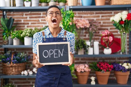 Photo for African american woman working at florist holding open sign angry and mad screaming frustrated and furious, shouting with anger looking up. - Royalty Free Image