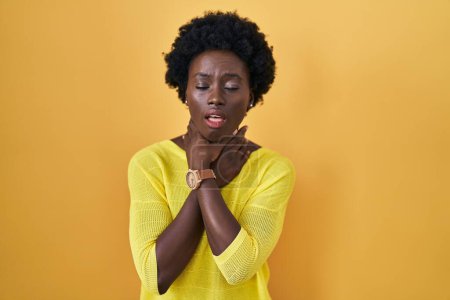 Téléchargez les photos : Jeune femme africaine debout au-dessus du studio jaune criant suffoquer parce étranglement douloureux. problème de santé. concept d'asphyxie et de suicide. - en image libre de droit