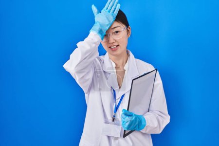 Téléchargez les photos : Jeune femme chinoise travaillant au laboratoire scientifique surpris avec la main sur la tête pour erreur, rappelez-vous erreur. oublié, mauvais concept de mémoire. - en image libre de droit
