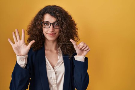 Téléchargez les photos : Hispanic woman with curly hair standing over yellow background showing and pointing up with fingers number six while smiling confident and happy. - en image libre de droit