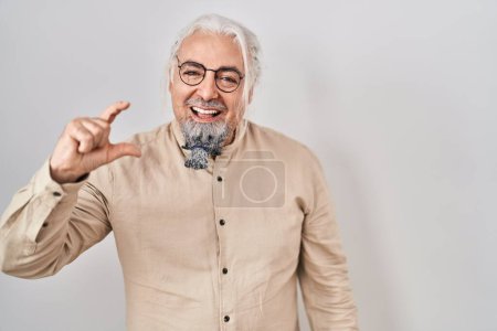 Téléchargez les photos : Middle age man with grey hair standing over isolated background smiling and confident gesturing with hand doing small size sign with fingers looking and the camera. measure concept. - en image libre de droit